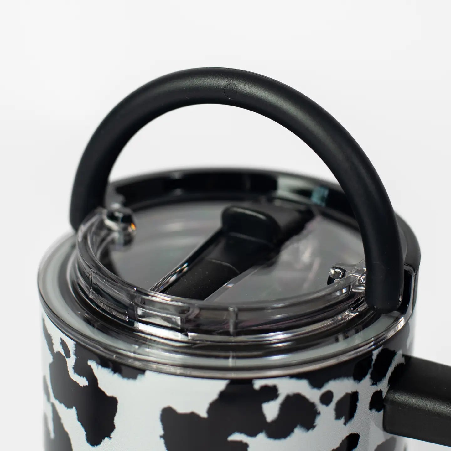Black and white cow print thermos with a clear lid on a white background