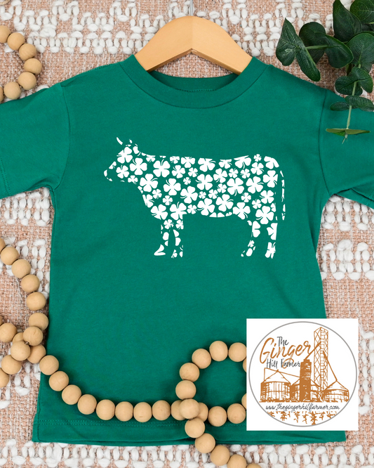 green tee with a cow made of clovers on a textured background
