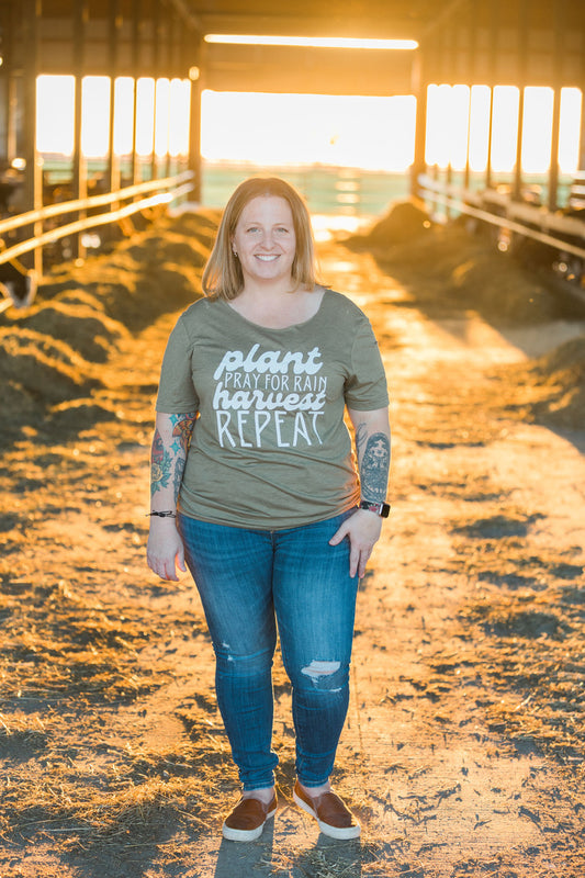 Woman standing in a barn wearing a shirt with a motivational quote.