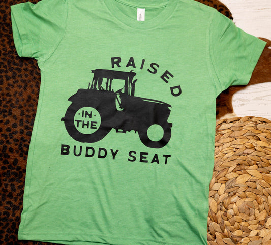 Green t-shirt with a black tractor graphic and text on a textured surface