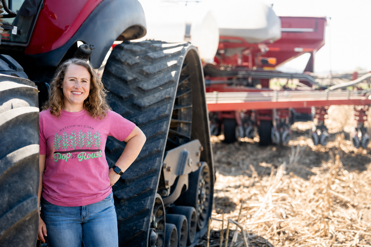 Woman in a pink shirt standing next to large agricultural equipment